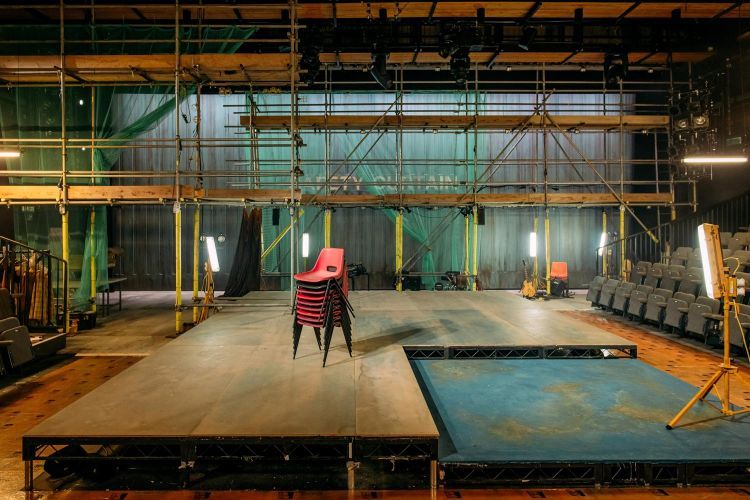 Empty set of Provok'd with a stack of chairs and scaffolding
